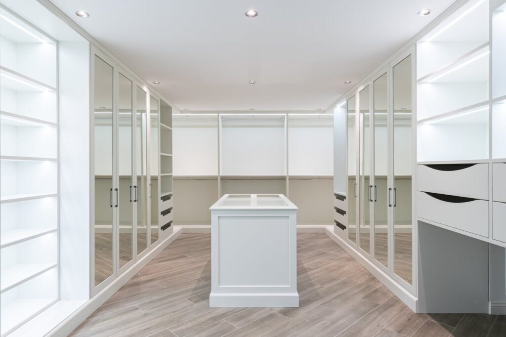 Luxury bespoke fitted wardrobes with mirrored doors and central island storage in modern walk-in dressing room